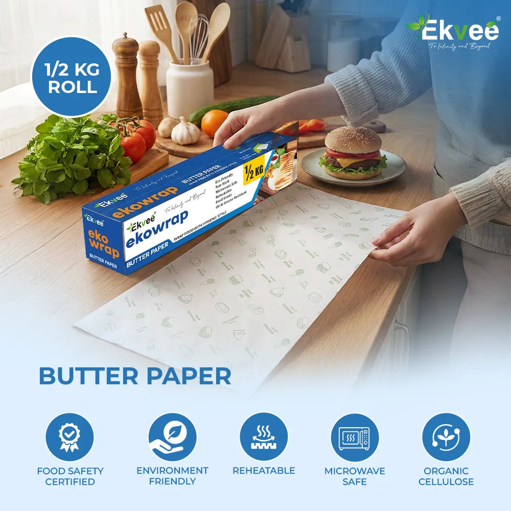 Ekowrap butter paper 500 g roll pack displayed on a kitchen counter, with a sheet of butter paper being pulled from the box. The image highlights that it is food-safety certified, environmentally friendly, reheatable, microwave safe, and made from organic cellulose.