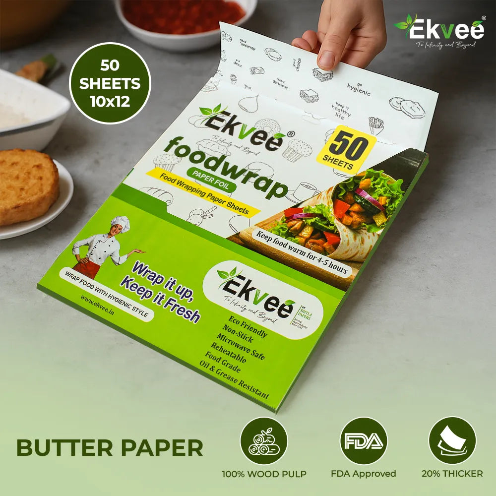 A hand holds an open package of Ekvee food wrap paper sheets, showing the white and green inner sheets. The packaging features illustrations of food items and a cartoon chef.