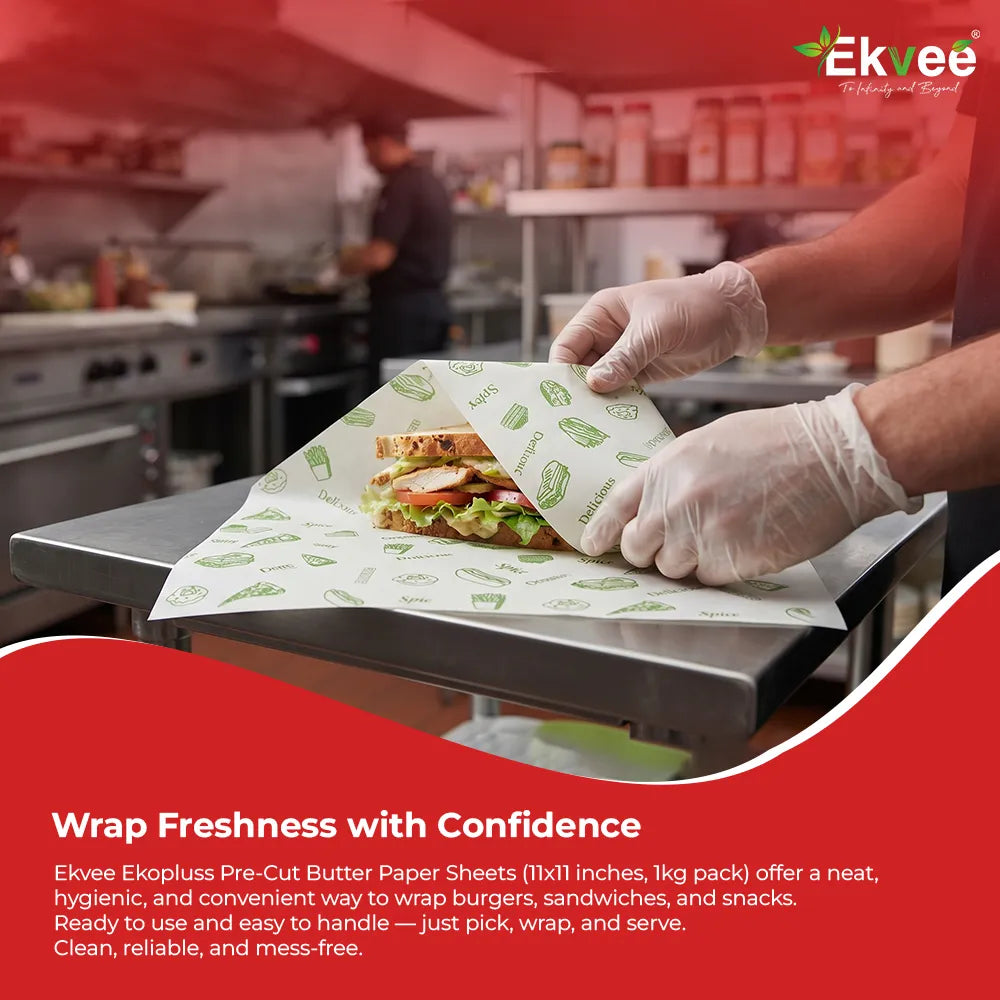Ekvee Ekopluss pre-cut butter paper sheets being used to wrap a fresh sandwich on a commercial kitchen counter, with a food-service kitchen in the background. The promotional image highlights hygienic, convenient, mess-free food wrapping.